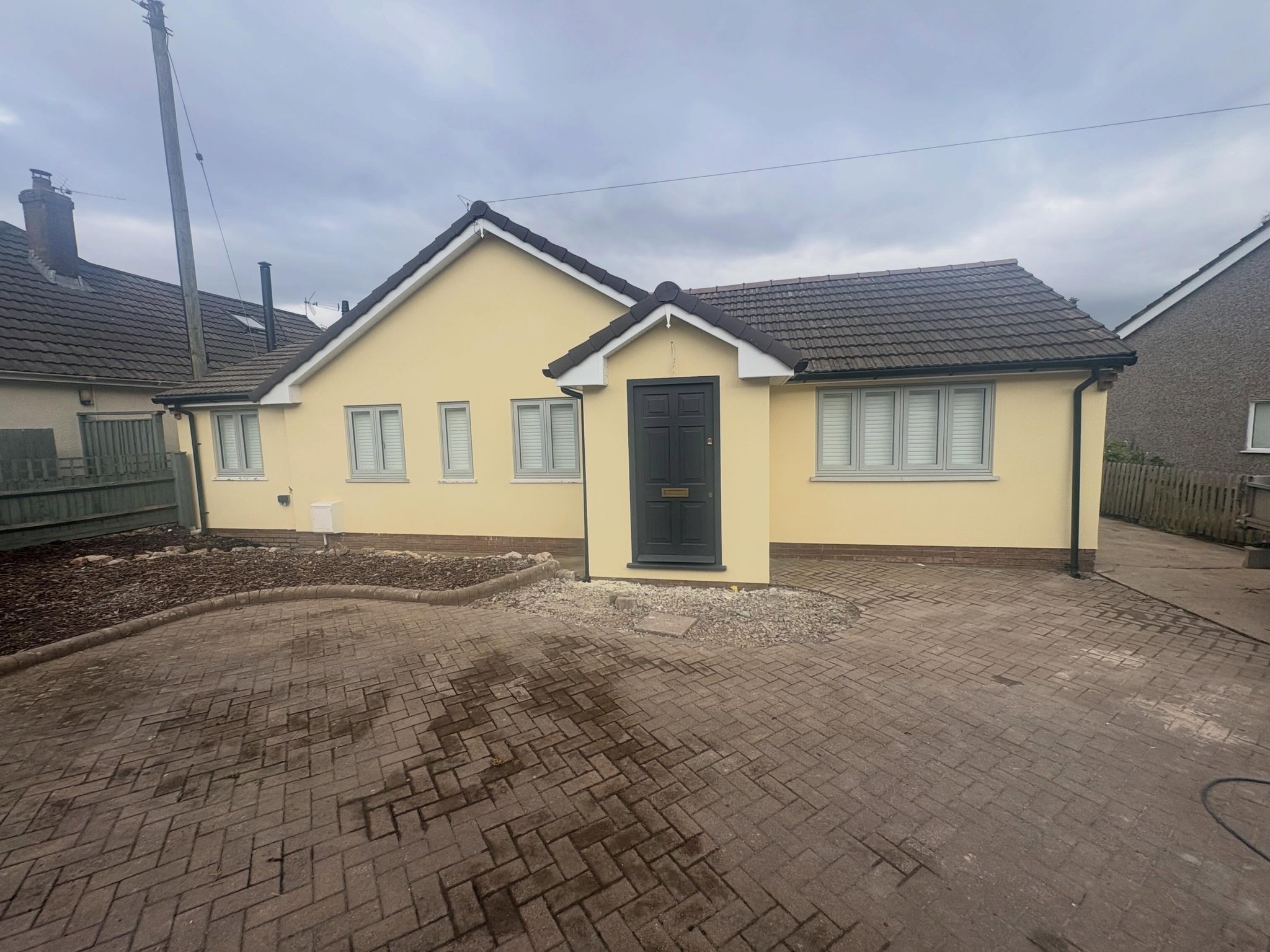 Bungalow finished in pale yellow silicone render, front view