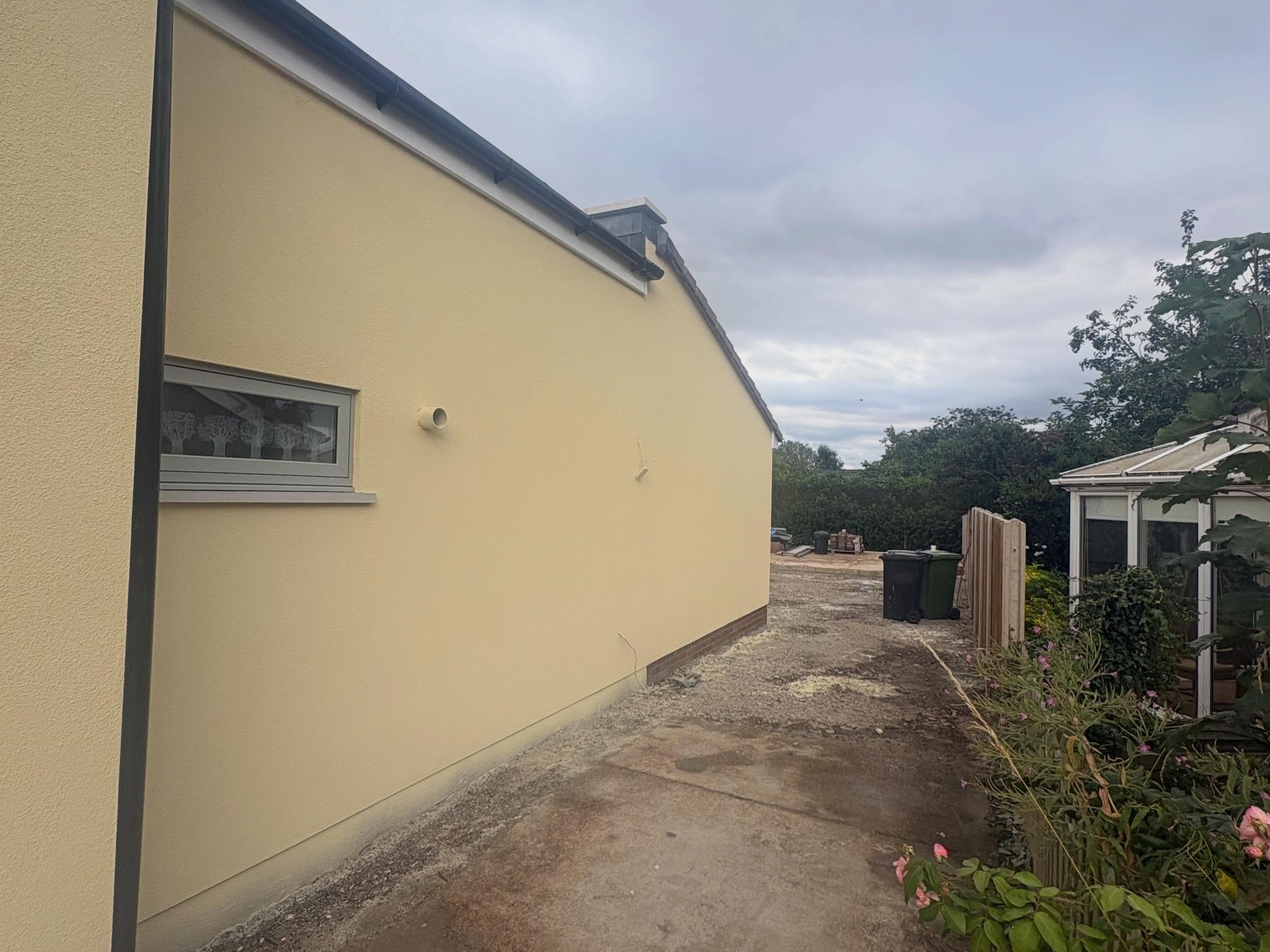 Side wall of the bungalow in smooth pale yellow render