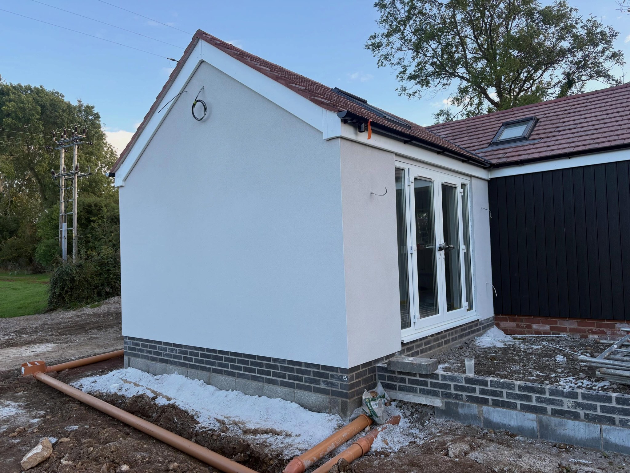 Off-white render meeting dark timber cladding