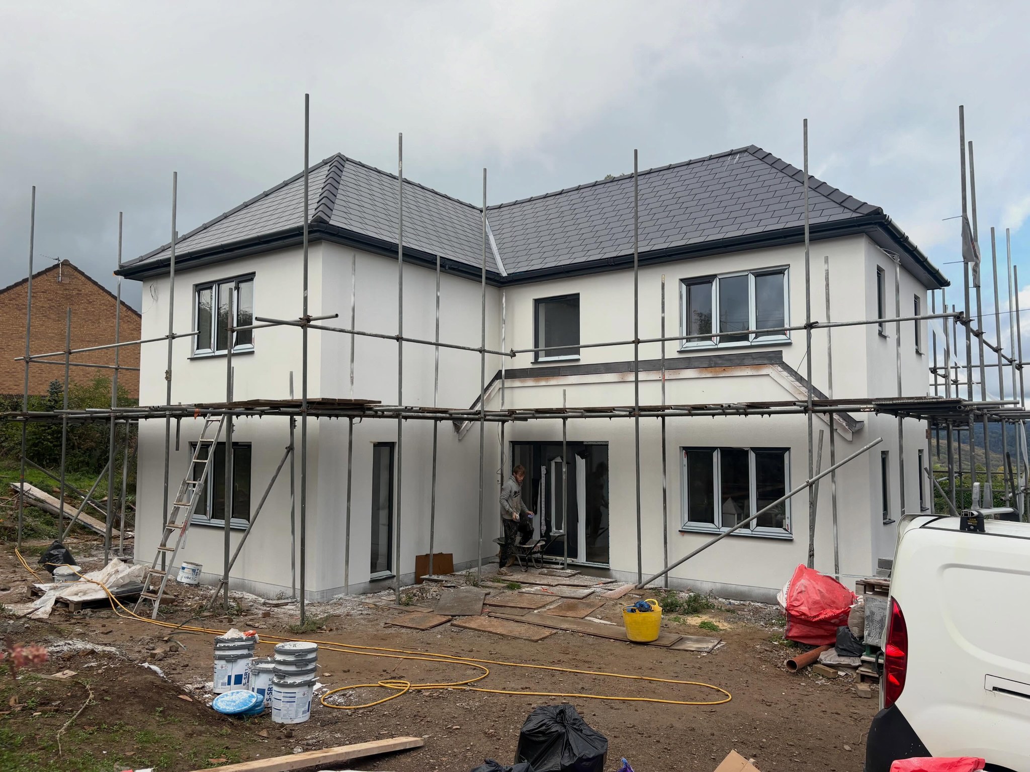 Rear of a large house mid-render, scaffolding up