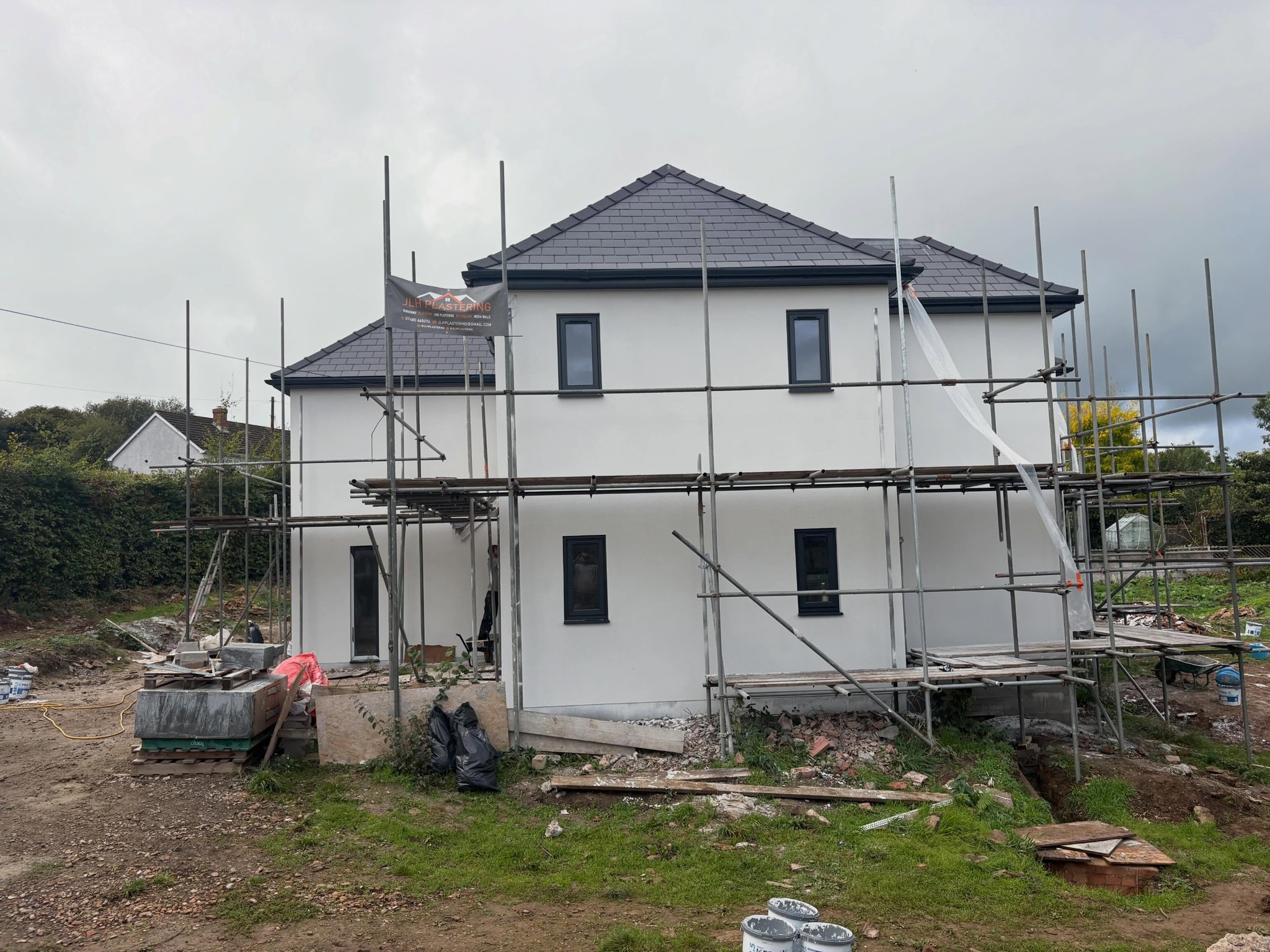 Front elevation rendered white behind the scaffold